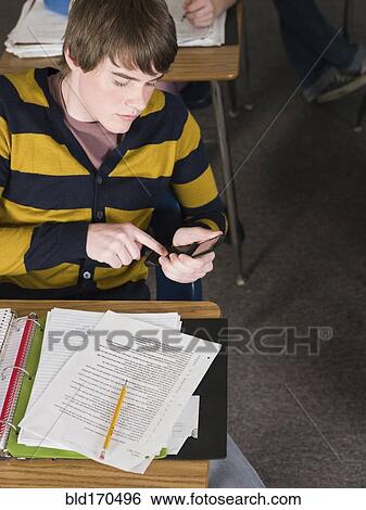 Student using cell phone at desk in classroom View Large Photo Image Stock Photograph - Student using cell phone at desk in classroom. Fotosearch