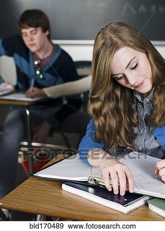 Student writing notes at desk in classroom View Large Photo Image Stock Photo - Student writing notes at desk in classroom. Fotosearch