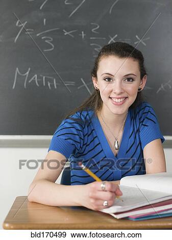 Stock Photo - Student writing notes at desk in classroom. Fotosearch