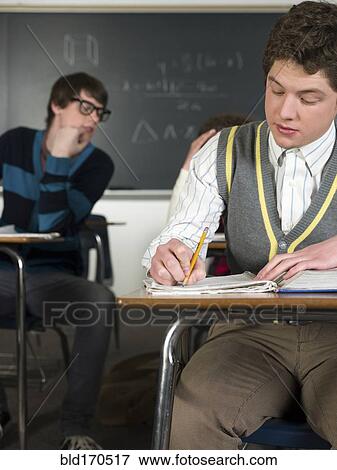 Student writing notes at desk in classroom View Large Photo Image Stock Photo - Student writing notes at desk in classroom. Fotosearch