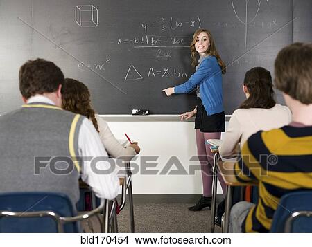 Picture - Student writing on chalkboard in classroom. Fotosearch