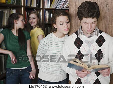 Stock Image - Students reading book in library. Fotosearch