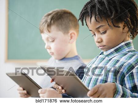 Stock Photograph - Students using digital tablet in classroom. Fotosearch