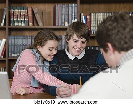 Students writing at desk in library View Large Photo Image Stock Photo - Students writing at desk in library. Fotosearch