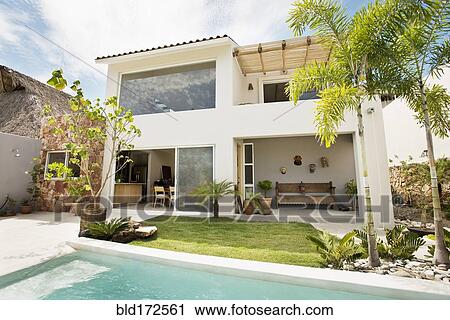 Stock Image - Swimming pool in backyard of modern home. Fotosearch