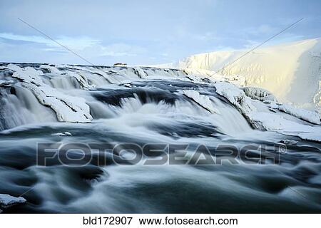 Stock Photo - Time lapse view of river flowing over icy rock formations. Fotosearch