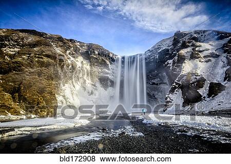 Stock Photo - Waterfall pouring over icy cliffs in remote landscape. Fotosearch
