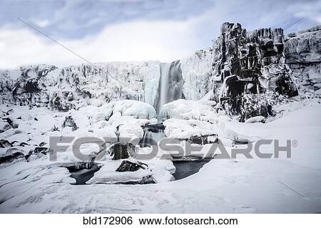 Stock Photograph - Waterfall pouring over icy cliffs in remote landscape. Fotosearch