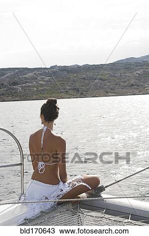 Stock Image - Woman admiring ocean from sailboat deck. Fotosearch