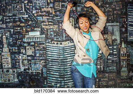 Picture - Woman dancing to headphones by mural. Fotosearch