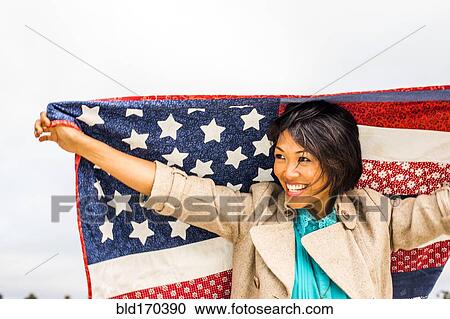 Stock Image - Woman holding American flag quilt outdoors. Fotosearch