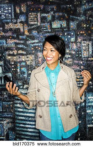 Stock Photography - Woman listening to cell phone by mural. Fotosearch