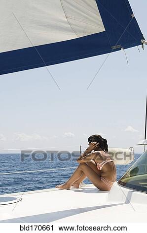 Stock Image - Woman sunbathing on sailboat deck. Fotosearch