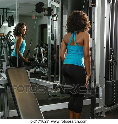 Woman using exercise machine in gymnasium View Large Photo Image Stock Photo - Woman using exercise machine in gymnasium. Fotosearch
