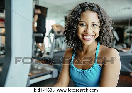 Stock Photography - Woman using exercise machine in gymnasium. Fotosearch