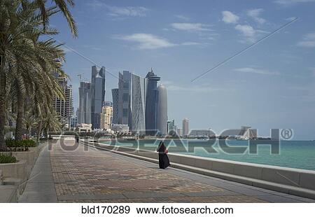 Stock Photo - Woman walking on Doha waterfront, Doha, Qatar. Fotosearch
