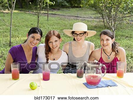 Women drinking juice outdoors at table View Large Photo Image Stock Photo - Women drinking juice outdoors at table. Fotosearch