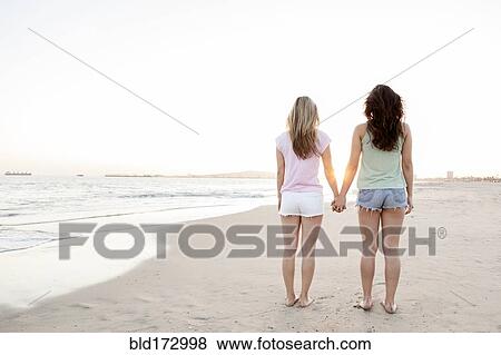 Stock Photo - Women holding hands on beach. Fotosearch