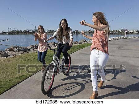 Stock Photography - Women running and bike riding at waterfront. Fotosearch