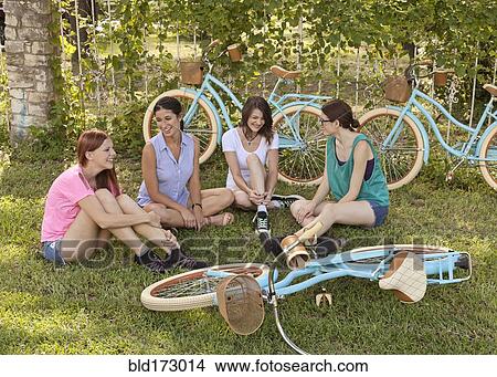 Women sitting with bicycles in grass View Large Photo Image Picture - Women sitting with bicycles in grass. Fotosearch