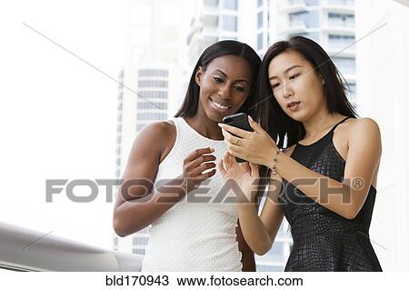 Women using cell phone on urban balcony View Large Photo Image Stock Image - Women using cell phone on urban balcony. Fotosearch