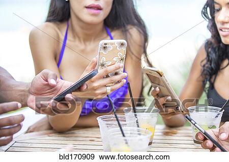 Stock Photo - Women using cell phones at lunch. Fotosearch