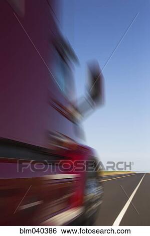 Stock Photograph - Blurred view of truck driving on remote highway. Fotosearch
