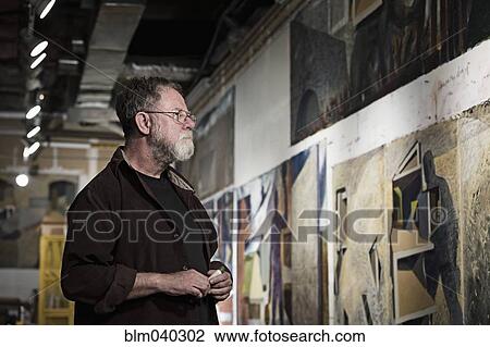 Stock Image - Caucasian artist admiring work in studio. Fotosearch