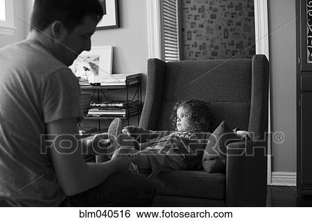 Stock Photograph - Caucasian father dressing daughter in living room. Fotosearch