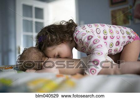 Stock Photo - Caucasian girl and baby sister playing on bed. Fotosearch