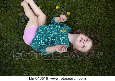 Stock Photo - Caucasian girl laying in grass. Fotosearch