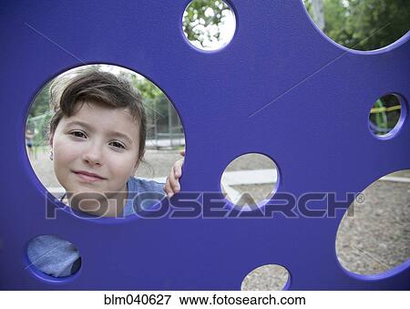 Stock Photo - Caucasian girl peeking through play structure. Fotosearch