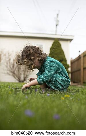 Stock Image - Caucasian girl playing in grass. Fotosearch