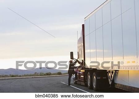 Stock Photography - Caucasian man climbing into truck on highway. Fotosearch
