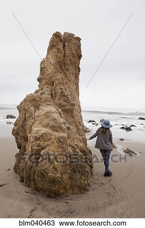 Stock Image - Caucasian teenage girl leaning on rock formation. Fotosearch