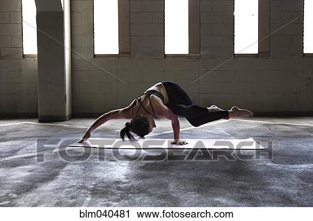 Stock Image - Caucasian woman practicing yoga in parking lot. Fotosearch
