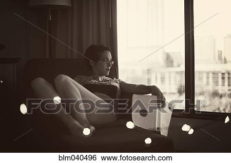 Stock Photograph - Caucasian woman reading in armchair. Fotosearch