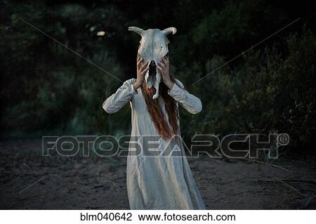 Stock Image - Caucasian woman wearing animal skull. Fotosearch