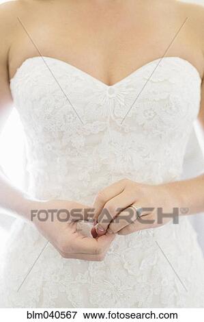 Stock Photo - Close up of bride wearing wedding dress and engagement ring. Fotosearch
