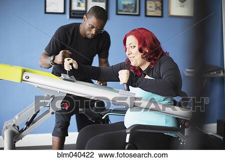 Stock Image - Disabled woman doing physical therapy with trainer. Fotosearch