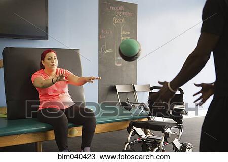 Stock Image - Disabled woman doing physical therapy with trainer. Fotosearch