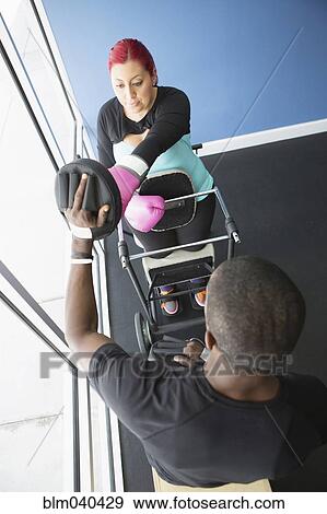 Stock Photo - Disabled woman doing physical therapy with trainer. Fotosearch