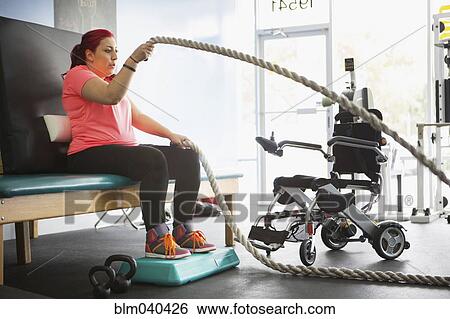 Stock Photograph - Disabled woman doing physical therapy in gym. Fotosearch