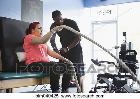 Stock Photography - Disabled woman doing physical therapy with trainer. Fotosearch