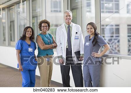 Stock Image - Doctor and nurses smiling in hospital hallway. Fotosearch