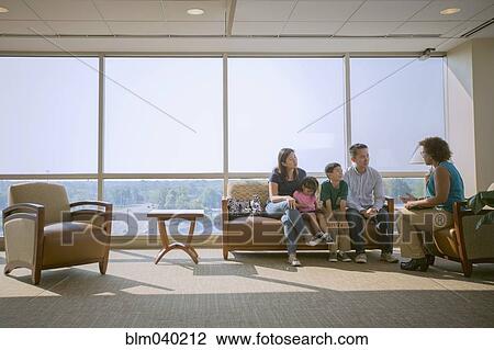 Stock Image - Doctor talking to patients in waiting room. Fotosearch