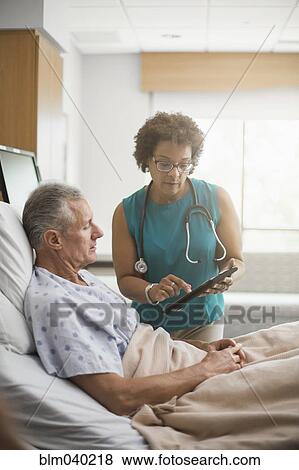 Stock Photo - Doctor using digital tablet with patient. Fotosearch