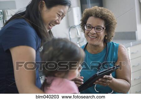 Stock Image - Doctor using digital tablet with patients. Fotosearch