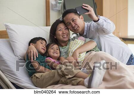 Picture - Family taking selfie with newborn baby. Fotosearch