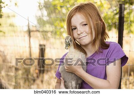 Stock Photograph - Girl holding duck on farm. Fotosearch